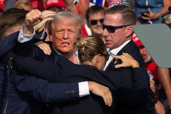 US Republican candidate Do<em></em>nald Trump is seen with blood on his face surrounded by secret service agents as he is taken off the stage at a campaign event at Butler Farm Show Inc. in Butler, Pennsylvania.