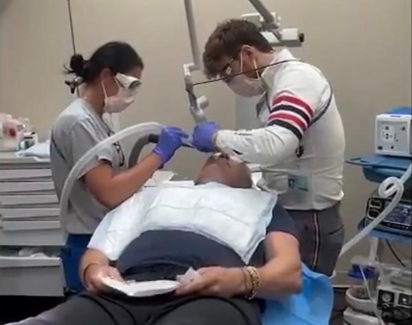 Doctors bending over Sam Champion. 