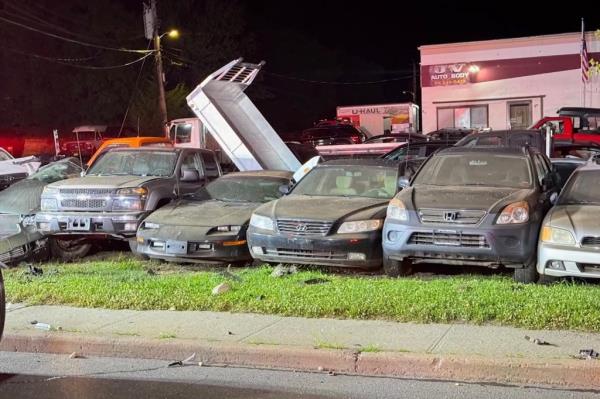 The wrecked car lies on top of other parked cars.