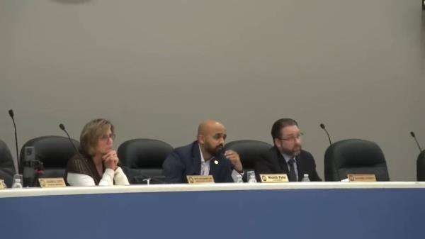 Police officer in co<em></em>nversation with a protesting resident holding an American flag at a town council meeting in Edison, New Jersey