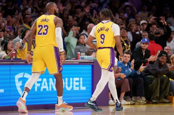 LeBron James and Bro<em></em>nny James checking into a basketball game against the Minnesota Timberwolves, both in yellow and white uniforms