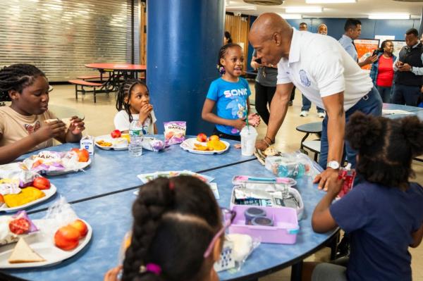 Mayor Eric Adams standing at a table with children during his visit to a Summer Rising site at Central Park East II, Manhattan.