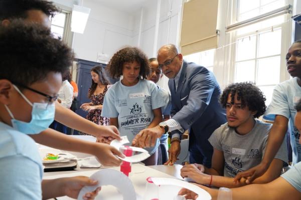 School Chancellor David Banks meeting with a group of kids around a table at PS 132 during a Summer Rising visit, participating in project