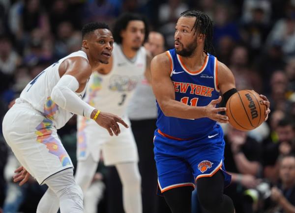 Knicks guard Jalen Brunson, right, looks to pass the ball as Denver Nuggets guard Russell Westbrook defends in the second half of an NBA basketball game Monday, Nov. 25, 2024, in Denver. 