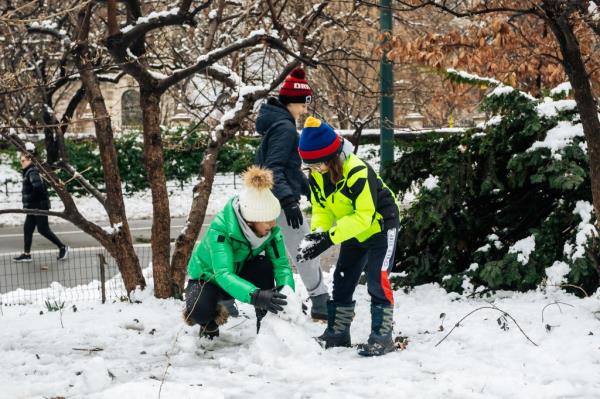 Deana Balahtsis-Thomas and her sons building a snow man outside. 