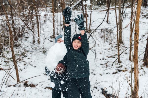 Tommy Mannarino and Ryan Mannarino playing football outside in the snow. 