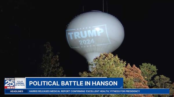 A large white water tower in Hanson, Mass. with 'Trump 2024' logo projected o<em></em>nto it from a nearby residential property.