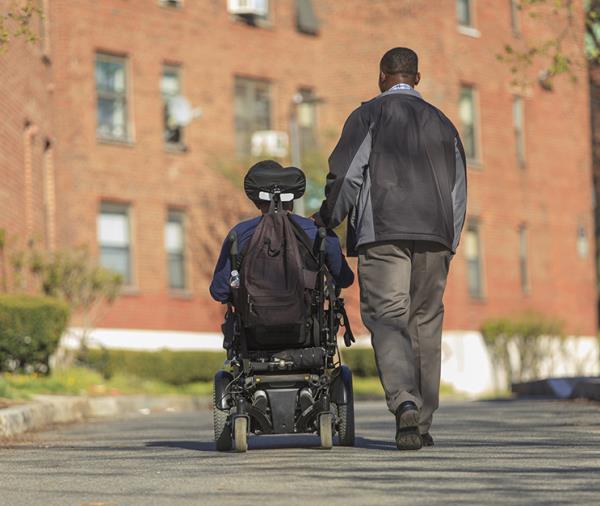 A person in a wheel-chair and their aide.