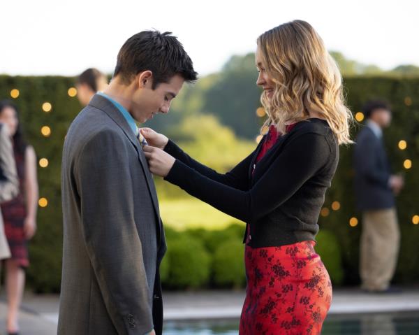 Megan (Sadie Stanley) and Luke (Griffin Gluck) standing by a pool in nice clothes while she adjusts his blazer. 