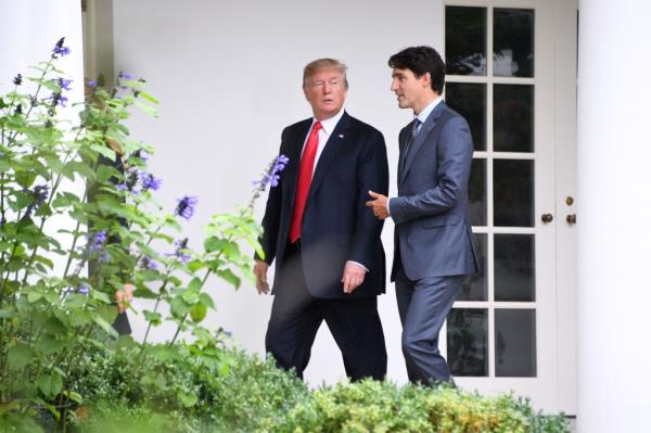 Do<em></em>nald Trump (L) listens to Canadian Prime Minister Justin Trudeau as they walk towards the Oval Office of the White House in Washington, DC, on October 11, 2017.