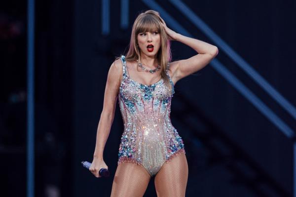 Taylor Swift performing on stage in a sparkly leotard, holding a microphone, during her Eras Tour in Lisbon, 2024