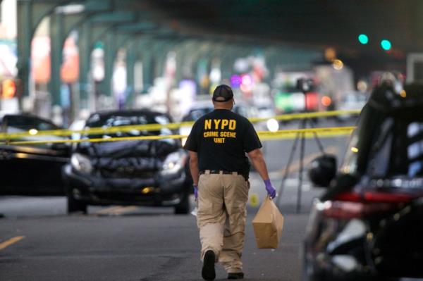 A crime scene unit police office removes evidence from the shooting scene.