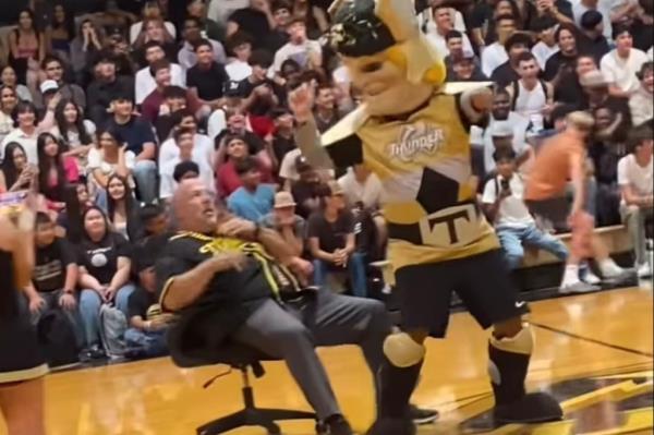 Another image of a mascot dancing with a man in a chair at a school rally.
