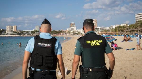 A French gendarme (L) and a Spanish civil guard patrol together along the beach in the Magaluf holiday resort in Calvia, on the Balearic island of Mallorca, on August 18, 2022 as part of a police internatio<em></em>nal collaboration in tourist areas. (Photo by JAIME REINA / AFP) (Photo by JAIME REINA/AFP via Getty Images)