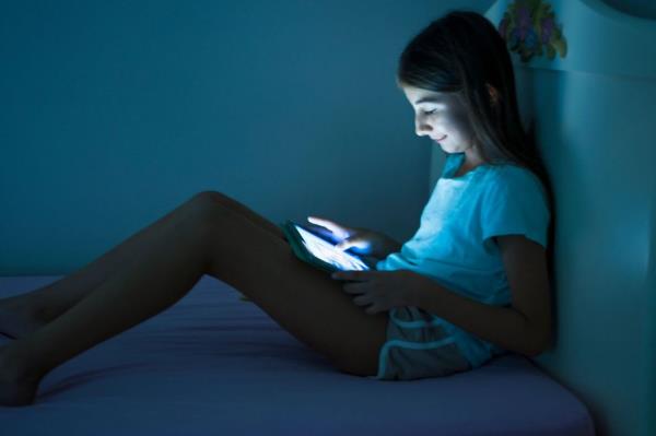 Little girl looking her digital tablet at night