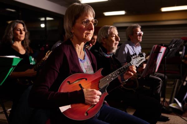 Judith Fallat, the orchestra's concertmaster, holds a mandolin in her hand