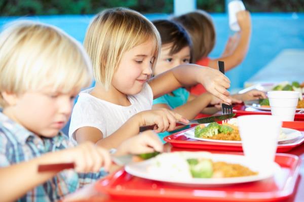 Group of elementary pupils enjoying a healthy lunch in the school cafeteria