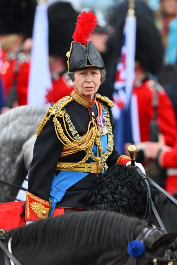 Princess Anne, in military uniform, riding horseback behind the gold state coach carrying King Charles III and Queen Camilla during their coronation