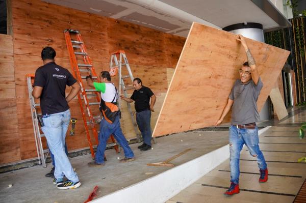 Workers place sheets of wood over windows and glass doors to protect them from the strong winds expected with the arrival of Hurricane Milton