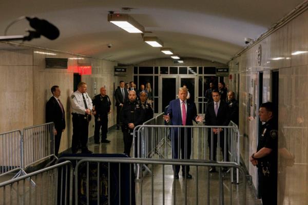 Former President Do<em></em>nald Trump and his lawyer Todd Blanche speaking to media after a court session in Manhattan Criminal Court, surrounded by police officers