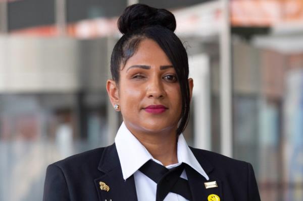 Elizabeth Gomes posing in her work uniform outside her workplace, expressing trauma from an unprovoked attack