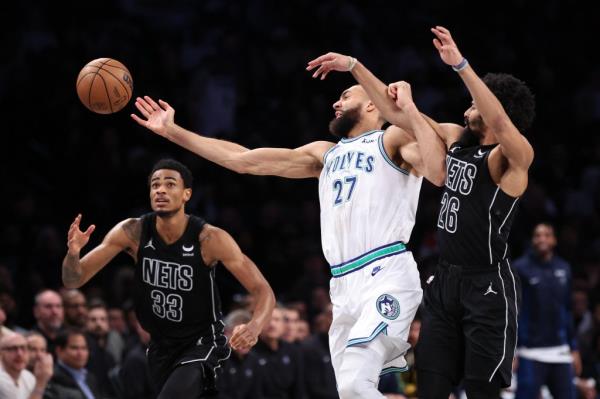 Minnesota Timberwolves center Rudy Gobert rebounds against Brooklyn Nets guard Spencer Dinwiddie and center Nic Claxton during basketball game.