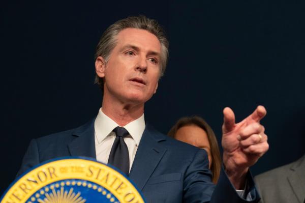 Gov. Gavin Newsom points from behind a podium.