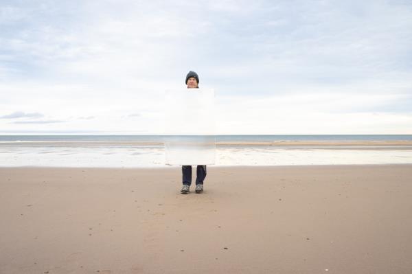 Man on the beach with torso hidden by invisibility shield