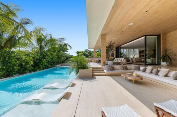 Luxurious waterfront property at 1510 W. 23rd St on Sunset Island III, featuring a pool with lounge chairs and deck chair