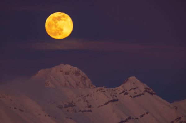 A moon over a snowy mountain, symbolizing NASA's effort to develop a standard time for the Moon and other planets.