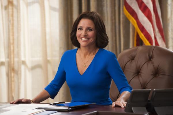 Julia Louis Dreyfus smiling next to an American flag. 