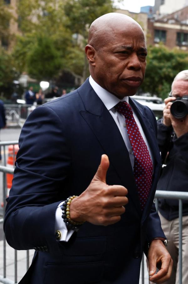 New York City Mayor Eric Adams in a suit, giving a thumbs up as he arrives at federal court