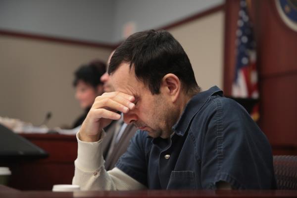 Nassar covers his face while listening to  victim impact statements during his sentencing hearing