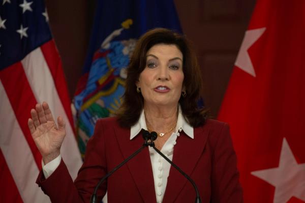 NY State Governor Kathy Hochul speaking at a podium in the 369th Regiment Armory, ho<em></em>noring the Natio<em></em>nal Guard and proposing changes to Medicaid costs.