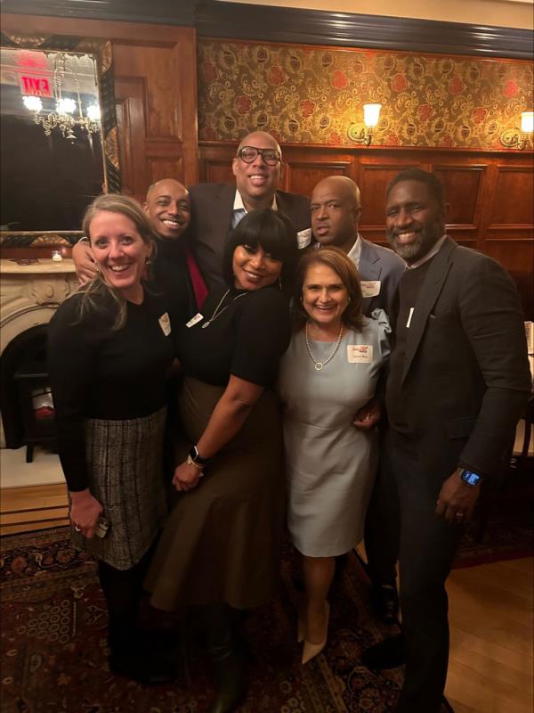 Superintendent Janice Ross in a light grey dress posing with Jason Green, co-founder and co-CEO of LINC, at an event alo<em></em>ngside a group