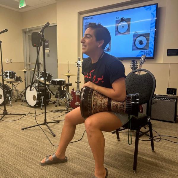 ibrahim banging a drum she holds on her lap