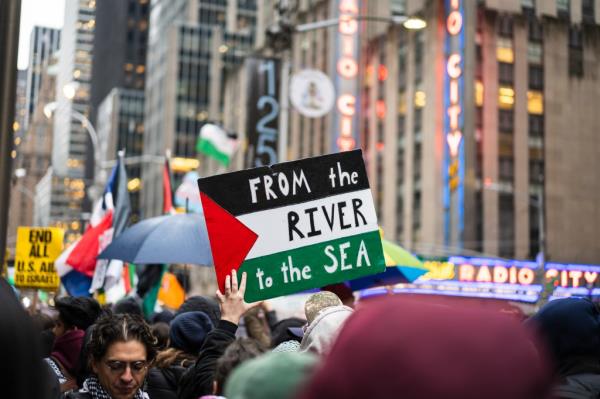 Protestor holding a sign reading 'from the river to the sea' outside Radio City Music Hall during a Palestine protest on March 28, 2024