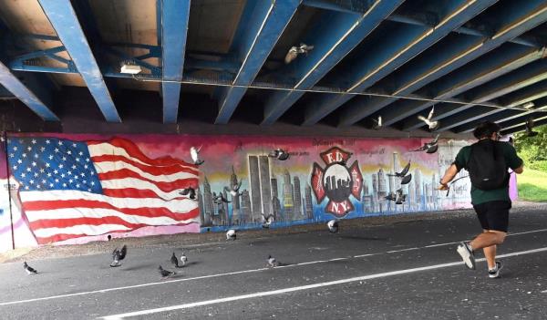 Jogger running with the mural in the background, as pigeons fly out of the runner's way