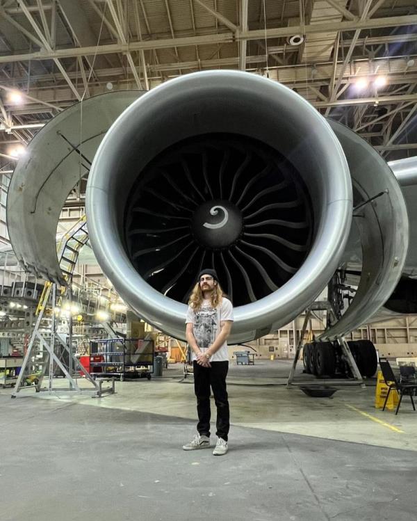 A man stands in front of a massive jet engine.