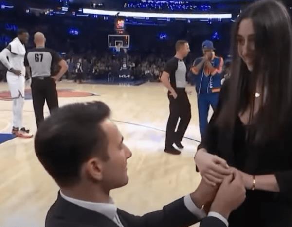 julius randle complains to a referee as an on-court proposal happens behind him.