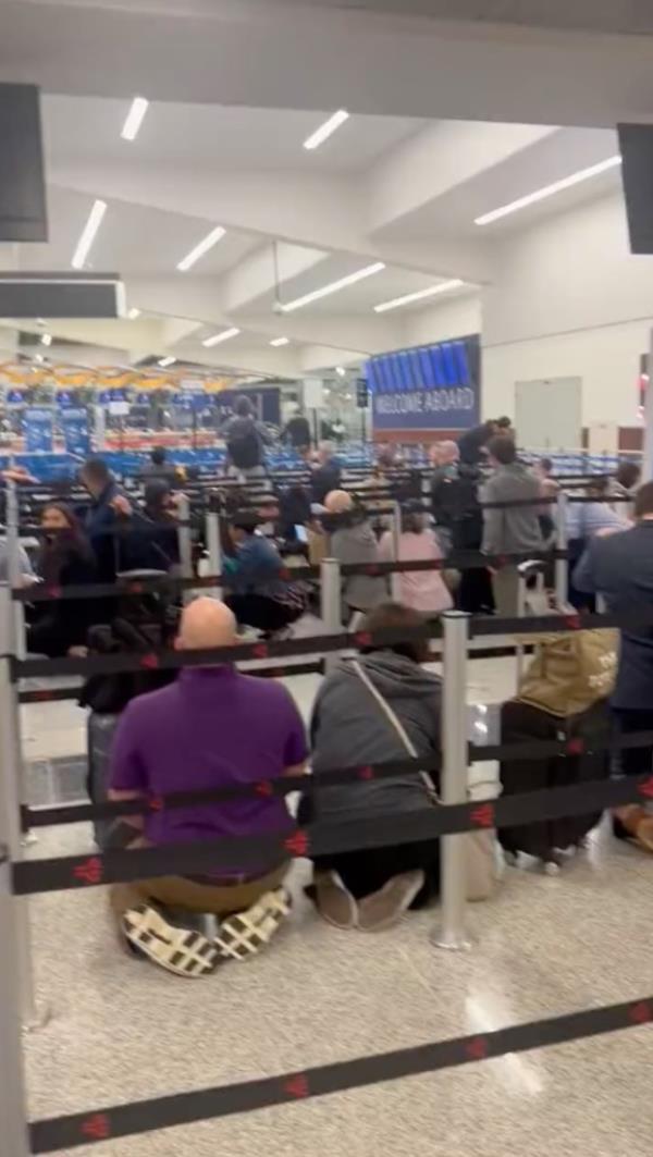 Travelers in the security line are seen front and center crouching down for safety. 