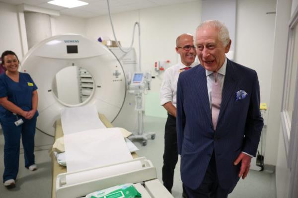 King Charles III and Cancer Research UK's Chief Clinician, Charlie Swanton, standing next to a CT scanner at the University College Hospital Macmillan Cancer Centre.