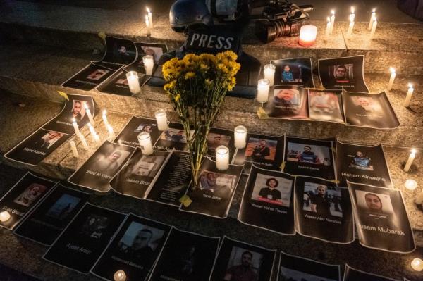 Flowers and candles are placed among pictures of journalists at a vigil in lower Manhattan.
