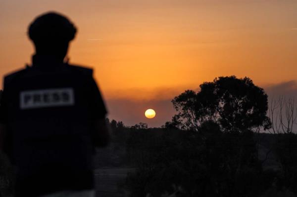A journalist looks on as the sun sets over the Gaza Strip off a position across the border in southern Israel.