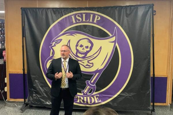 A picture of Dennis O'Hara standing before an Islip Schools banner.