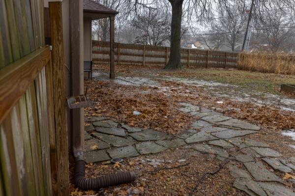 A leaf-strewn backyard with signs of melted snow and unraked leaves.