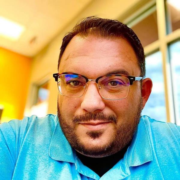 A photo of David Harrington wearing glasses and a blue shirt.