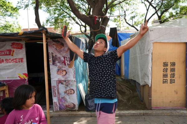 Venezuelan migrant Eliezer López celebrating in a tent encampment in Mexico City after securing an asylum appointment through the U.S. Customs and Border Protection's mobile app