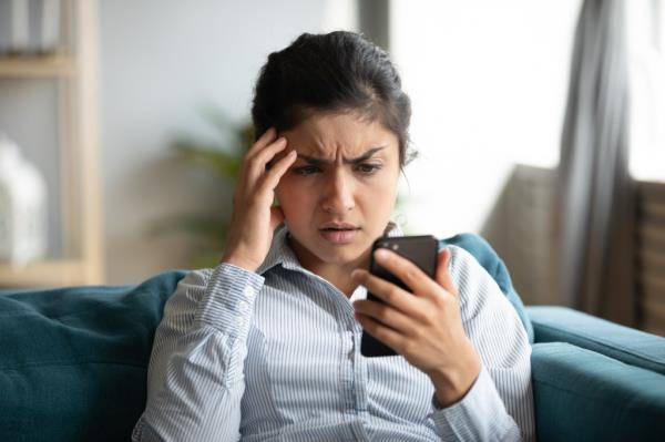 Woman looking at her cell phone in distress