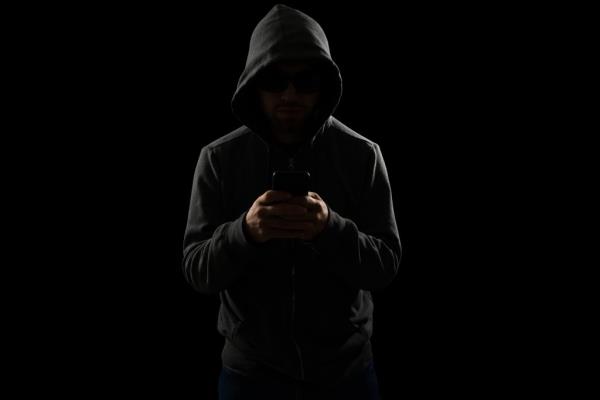 Hooded suspicious person on phone in dark